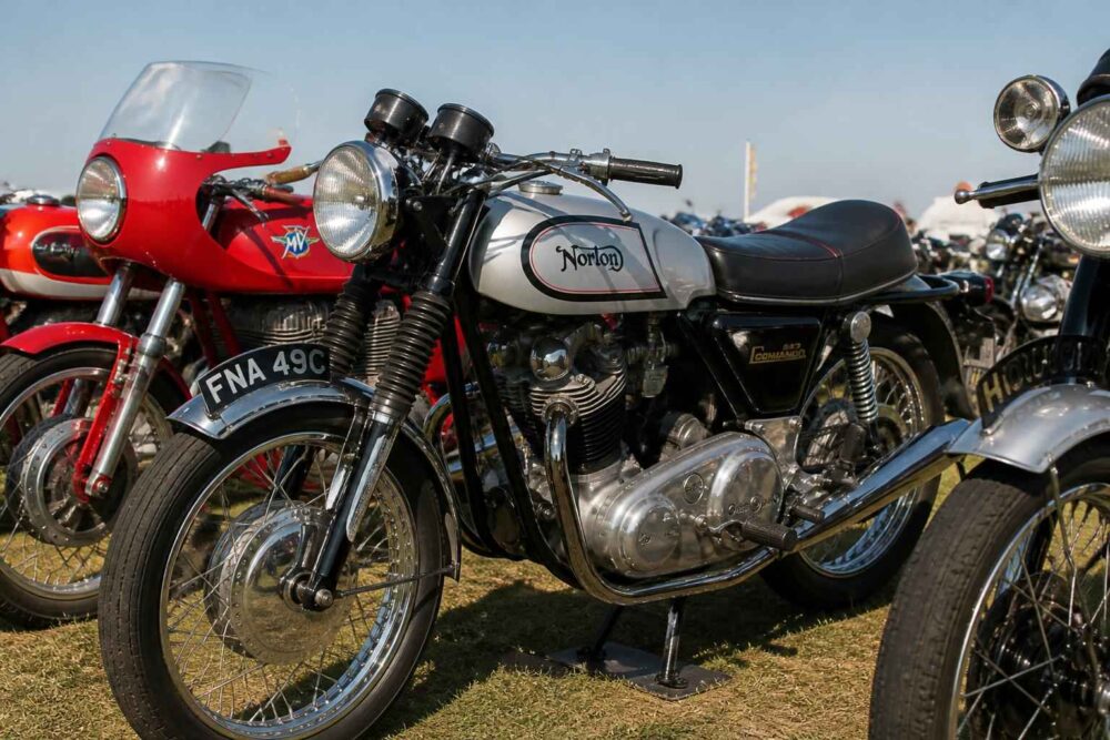 Klasyczny motocykl Norton wśród zabytkowych maszyn Klasyczny motocykl Norton z czarno-srebrnym zbiornikiem na plenerowej wystawie motocykli