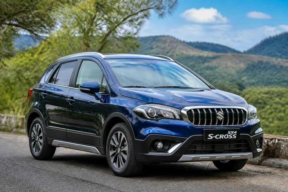 Niebieski Suzuki SX4 S-Cross zaparkowany na górskiej drodze wśród zieleni i wzgórz