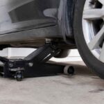 Samochód uniesiony na czarnym podnośniku hydraulicznym podczas wymiany koła lub naprawy podwozia