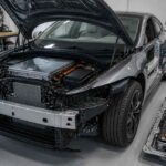 Elektryczny samochód z otwartą maską i odsłoniętymi podzespołami w hali produkcyjnej