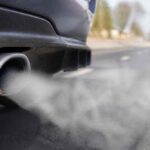 Rura wydechowa samochodu emitująca białe spaliny na drodze jesienią